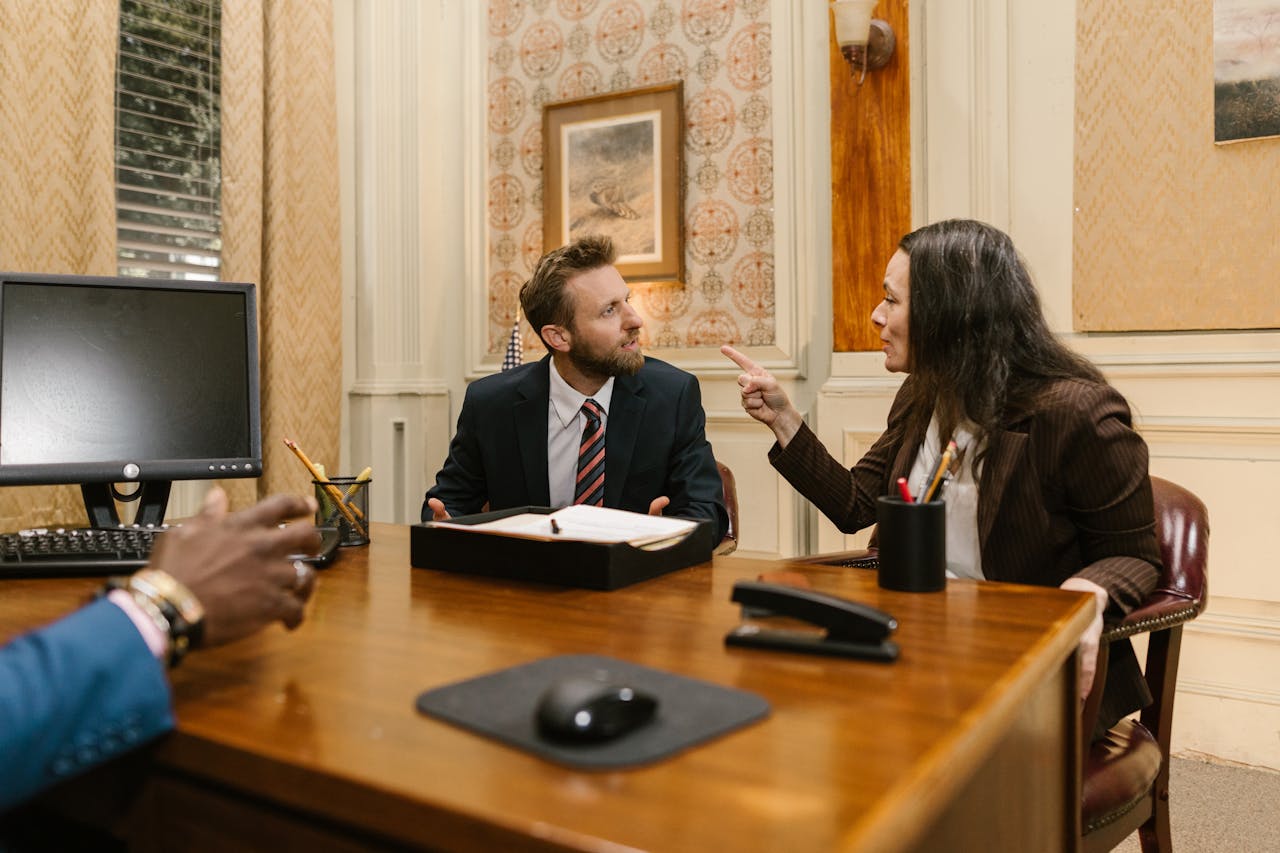 creative Professionals engaged in a serious discussion inside a law office with a computer on the desk.